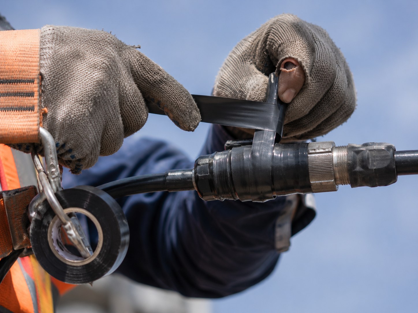 Weatherproofing tape being applied to a connector at height.